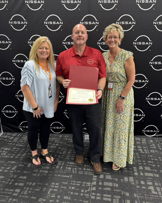 Superintendent, CTE Director standing beside the Nissan Center of Excellence instructor joining Tullahoma High School. All are smiling as the instructor holds the certificate commemorating this new partnership.