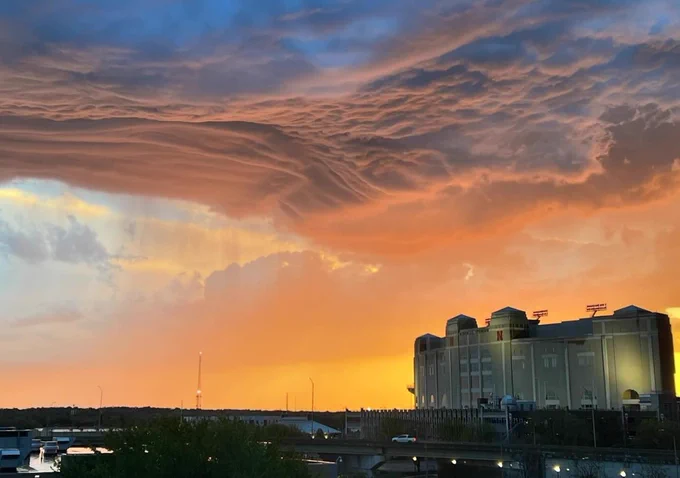 The sun sets over Memorial Stadium after a storm, creating orange heavy clouds