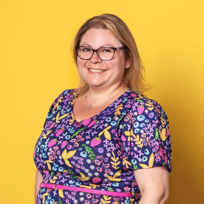 Portrait shot of midwifery lecturer, Karen Henry, in front of a yellow background.