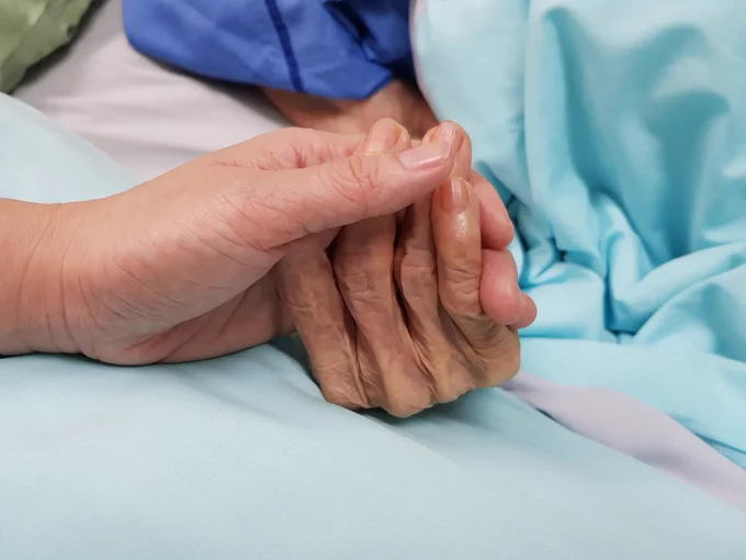 Up-close image of people holding hands in a hospital setting