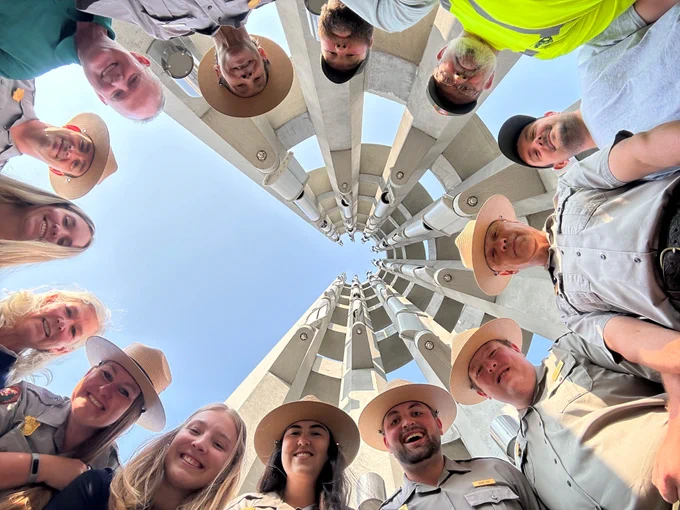 Image 1: Park Rangers from multiple divisions and the Friends of Flight 93 National Memorial stand in a circle under the Tower of Voices. NPS Photo.