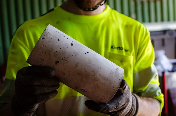 Henkilö pitää kädessään harmaata betonista valettua lieriön muotoista kappaletta.