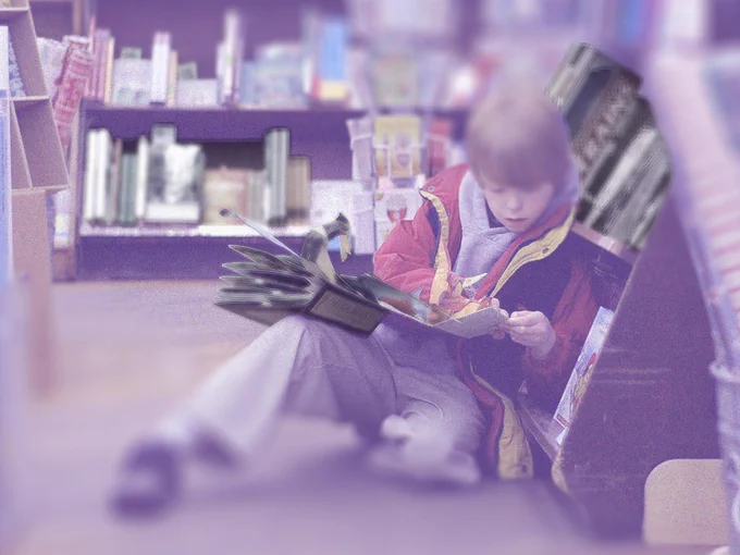 Distorted image of a boy reading while leaning against a library shelf.
