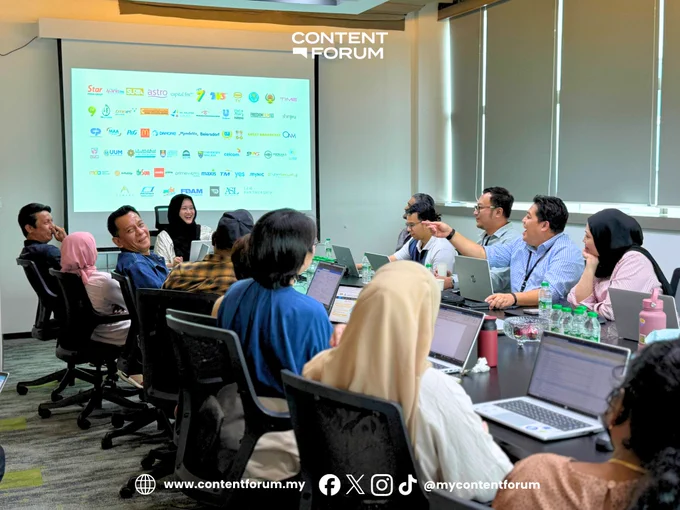 Group of people seated in a meeting room, discussing and smiling.