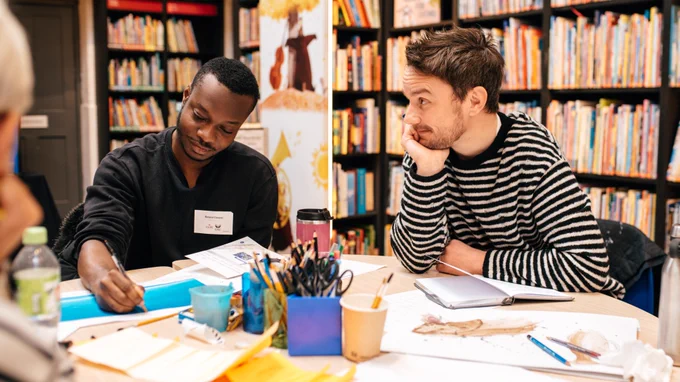 Two people sitting and writing at a table.