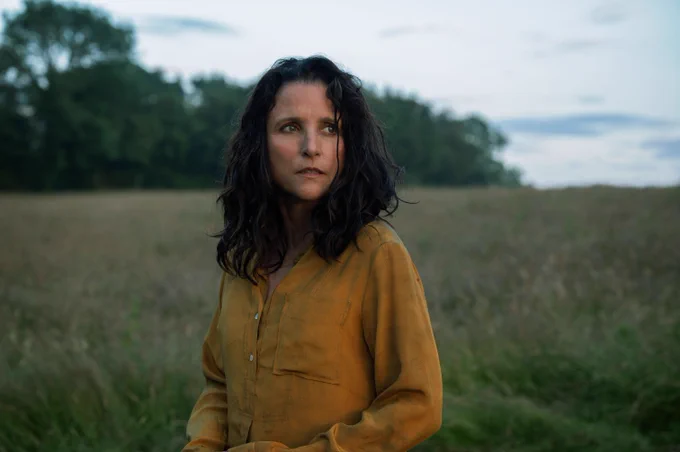 Still from Tuesday showing woman in a field looking sad.