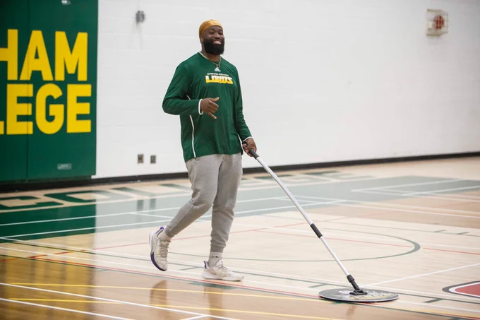 Student staff sweeping the basketball court.