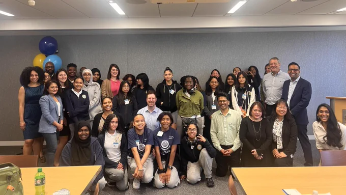 Students and employees pose together in an office setting. 