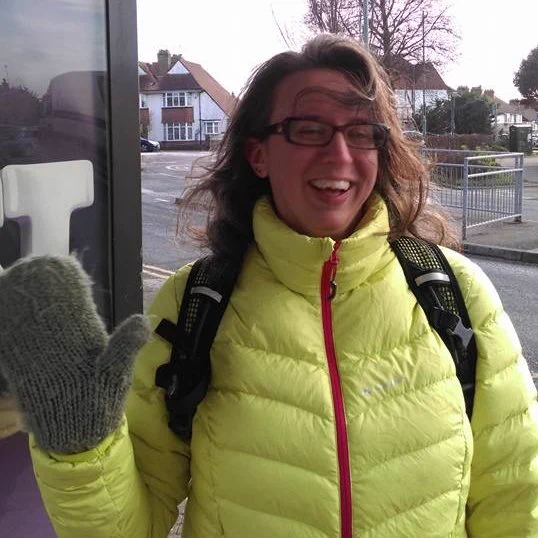 Me in a bright yellow puffa jacket, waving by bus stop