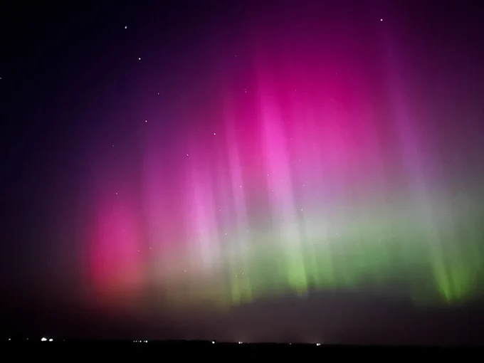 A dazzling aurora lights up the night sky. Shades of pinkish-purple near the top give wy to bands of white and green. Credit: NASA/Carina Alden 