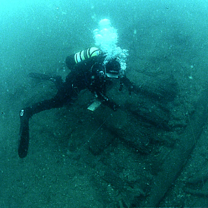A photograph of a diver looking at a ship wreck.