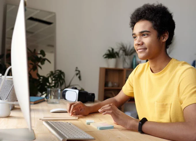 Photo of a male wearing a yellow tshirt using an computer
