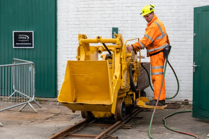 a mine guide operating a yellow rocker shovel in the Museum grounds
