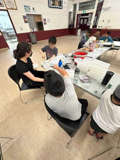 Jacklyn (pictured in black) running her event at the  Hamlet of Kugluktuk summer camp, posed doing mini experiments with the children of the community. 