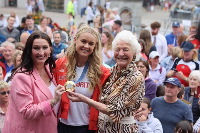 Hannah Scott on stage with her medal, pictured alongside Deputy First Minister Emma Little Pengelly and Olympic Gold medal winner Lady Mary Peters.
