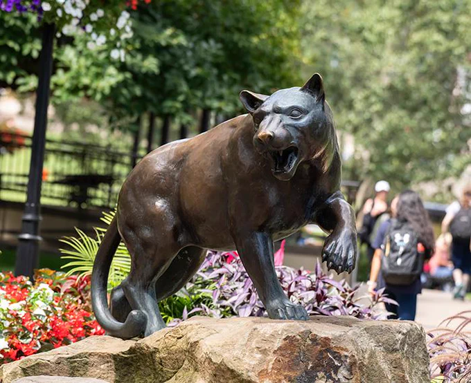 Bronze statue of a snarling panther positioned on a rock.