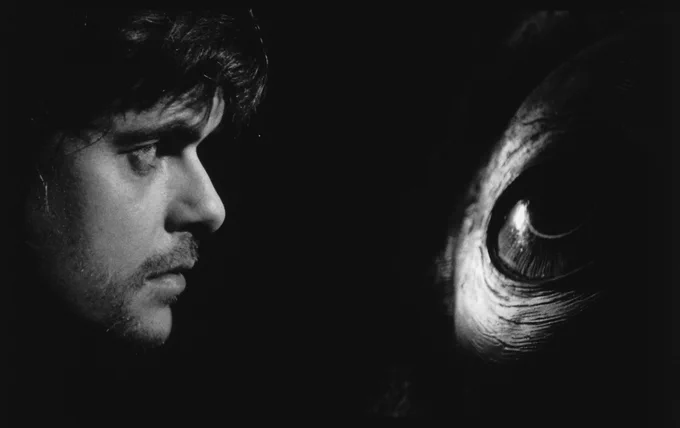 Still from Werckmeister Harmonies showing man looking worried into a shadowy giant eye.
