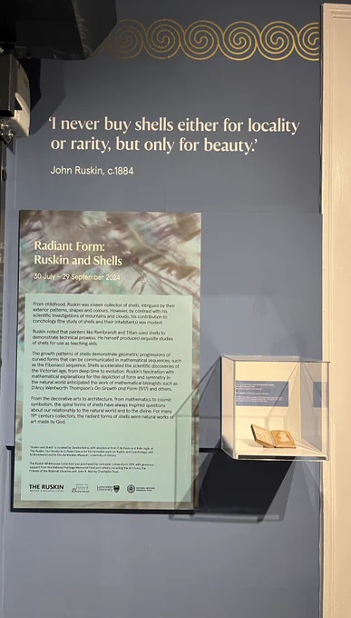 A photograph of a text panel in an exhibition. Next to the text panel is a small leather case containing a shell cameo portrait of John Ruskin. 