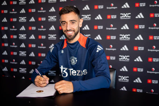 Bruno Fernandes smiles as he signs his new United contract.