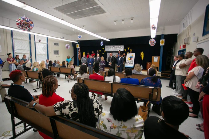 people seated in a room watching to people on a stage speak