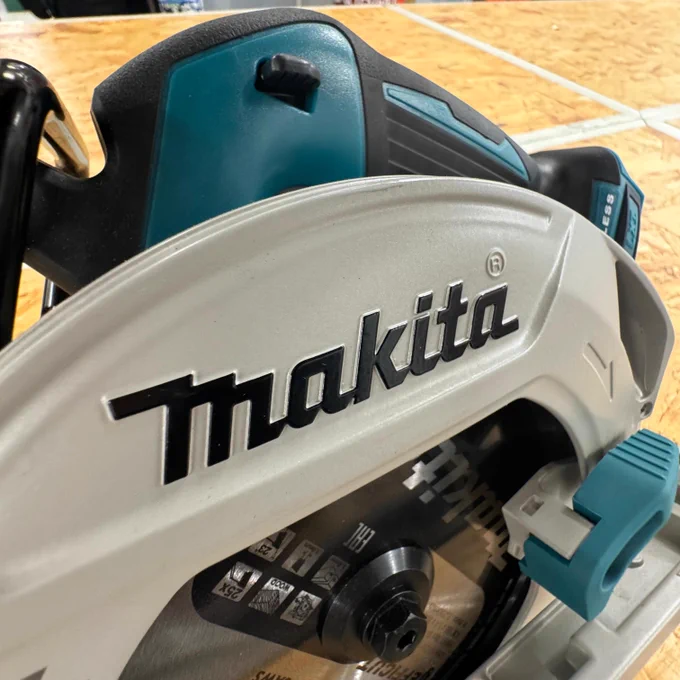 Close-up view of a Makita circular saw on a wooden surface, emphasizing the tool's details and branding.