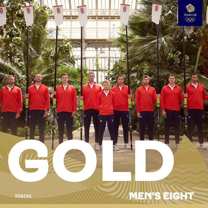 Eight athletes dressed in team uniforms stand in a row holding oars, inside a greenhouse, under banners with Olympic rings and "Team GB". The word "GOLD" is prominently displayed at the bottom, along with "MEN'S EIGHT" and a rowing icon, indicating a victory at the Olympics.