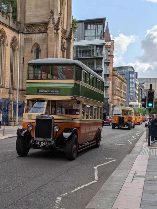 a selection of vintage Glasgow buses driving through the city centre