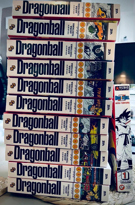 11 (3 in 1) Dragonball manga volumes lined up to form a continuous, colourful spine artwork featuring characters and racing scene from the series.