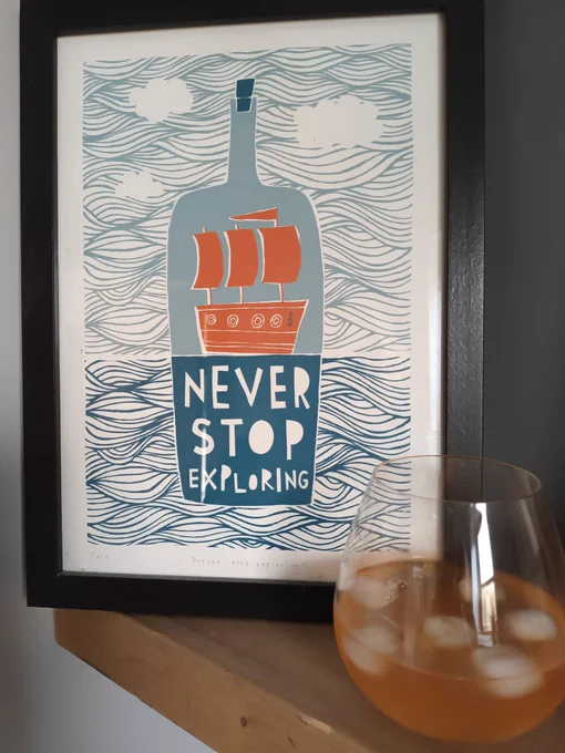 Picture of a ship in a bottle. Next to it is a glass with a yellow liquid and ice.