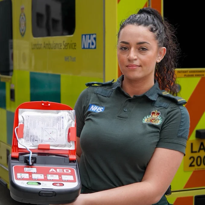 A paramedic holding up a defib.
