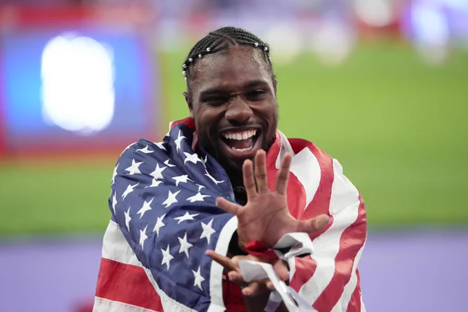Noah Lyles posing with the American flag after winning the men's 100m.