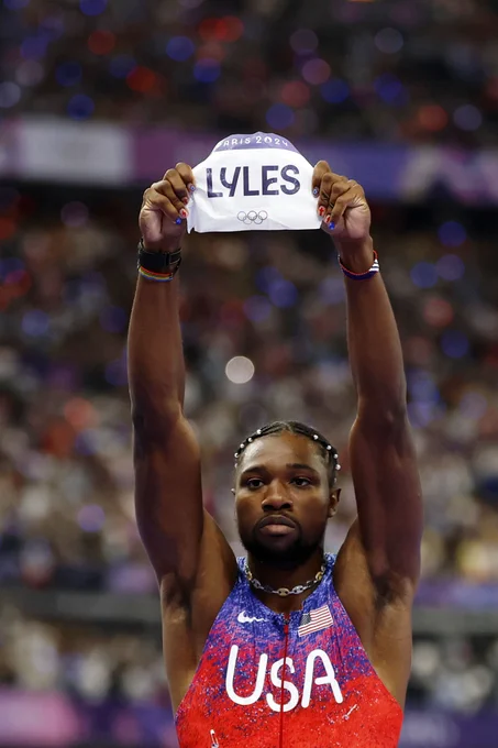Noah Lyles holding up his name tag that says "Lyles" after his race.