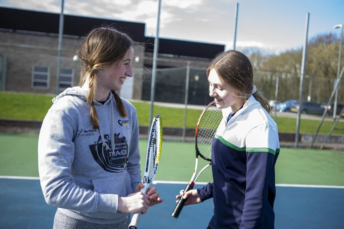two teenage girls playing tennis