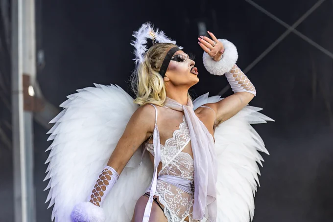 Drag queen dressed as an angel looking out to crowd.