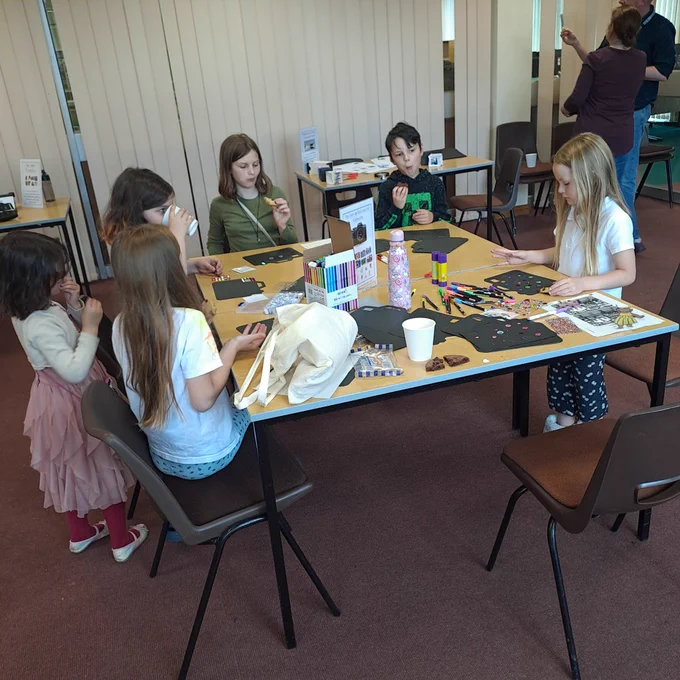 Five young people decorating stencils of cameras 