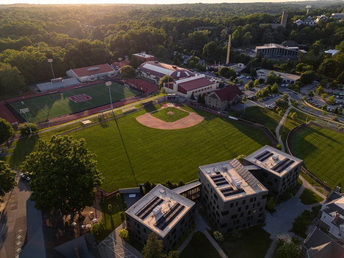 Drone image of baseball fields, a track and buildings on Swarthmore's campus during sunset.