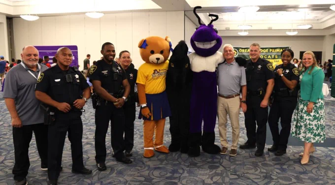 Members of the Commmunity standing with school mascots