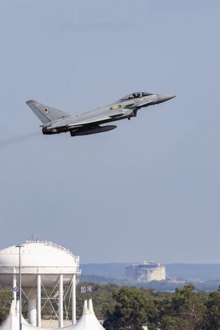 Typhoon taking off with blue skies in the background and trees below.