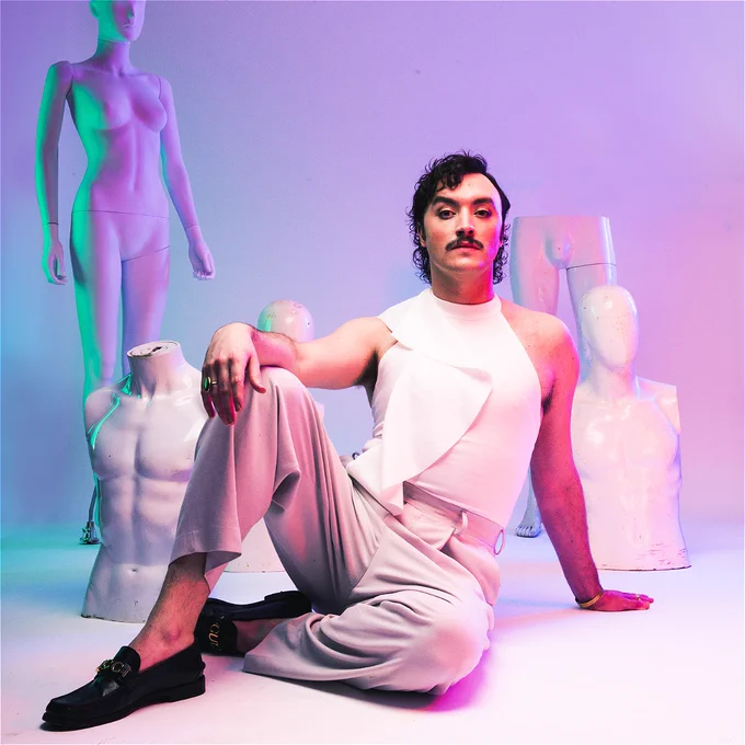 A photo of Dan Wye wearing a white outfit surrounded by mannequins
