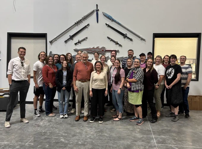 Warehouse team standing in front of weapons display wall!