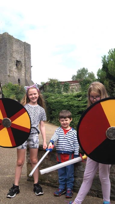 Three children with shields and foam swords with Clitheroe Castle in the background.