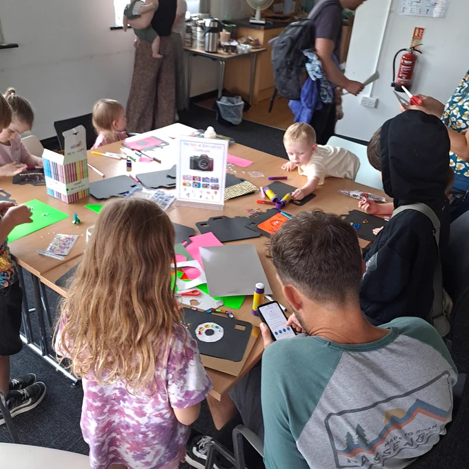 Young people and adults taking part in craft activities around a table 