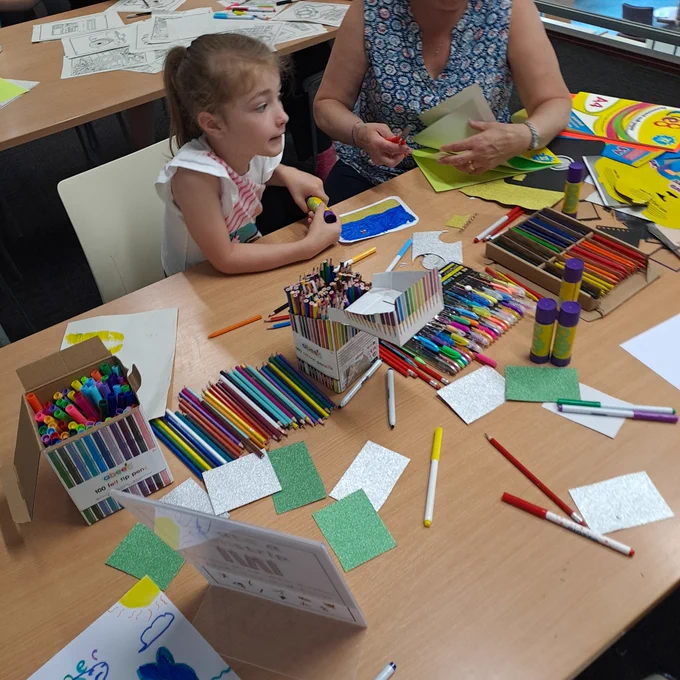 A table full of crayons and colouring which a family taking part 