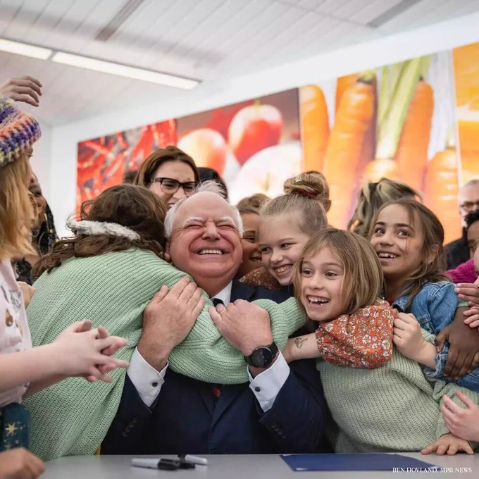 Tim Walz celebrating with kids after signing a bill providing free breakfast and lunch to Minnesota students