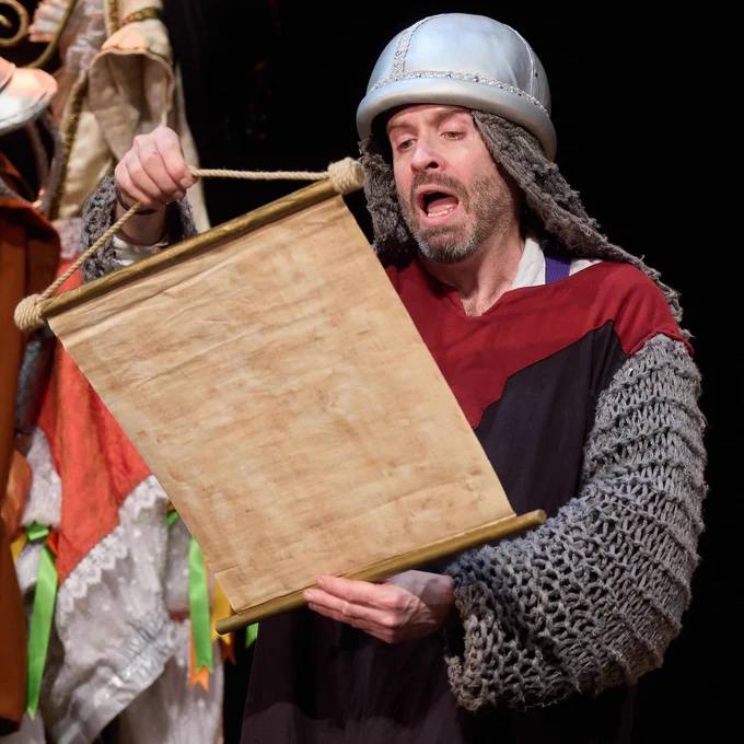 A photo from Rotten Royals of a cast member reading an old scroll.
