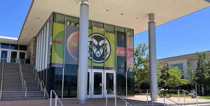 Colorado State University's Lory Student Center stands under the sun covered with CSU "Find Your Energy" branding displayed on it's large windows. 