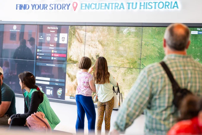Two children interacting with a map on a large TV display