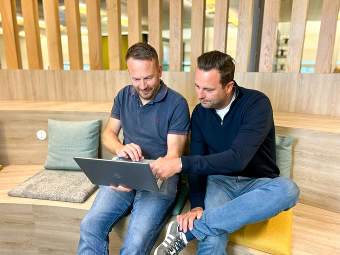 Two colleagues working on a laptop in one of our digital hubs