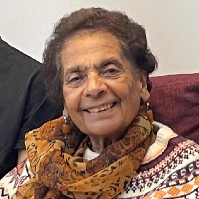 A modern day picture of Gulzar at her home, she is smiling and wearing a light scarf. 
