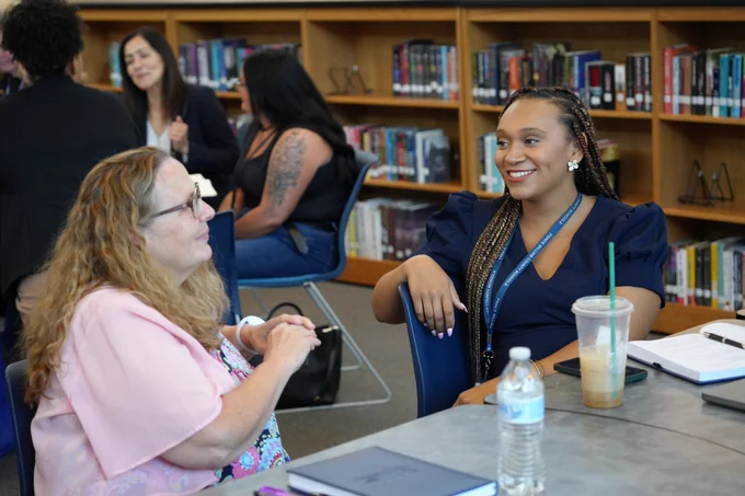 Two staff members speaking with each other and smiling.